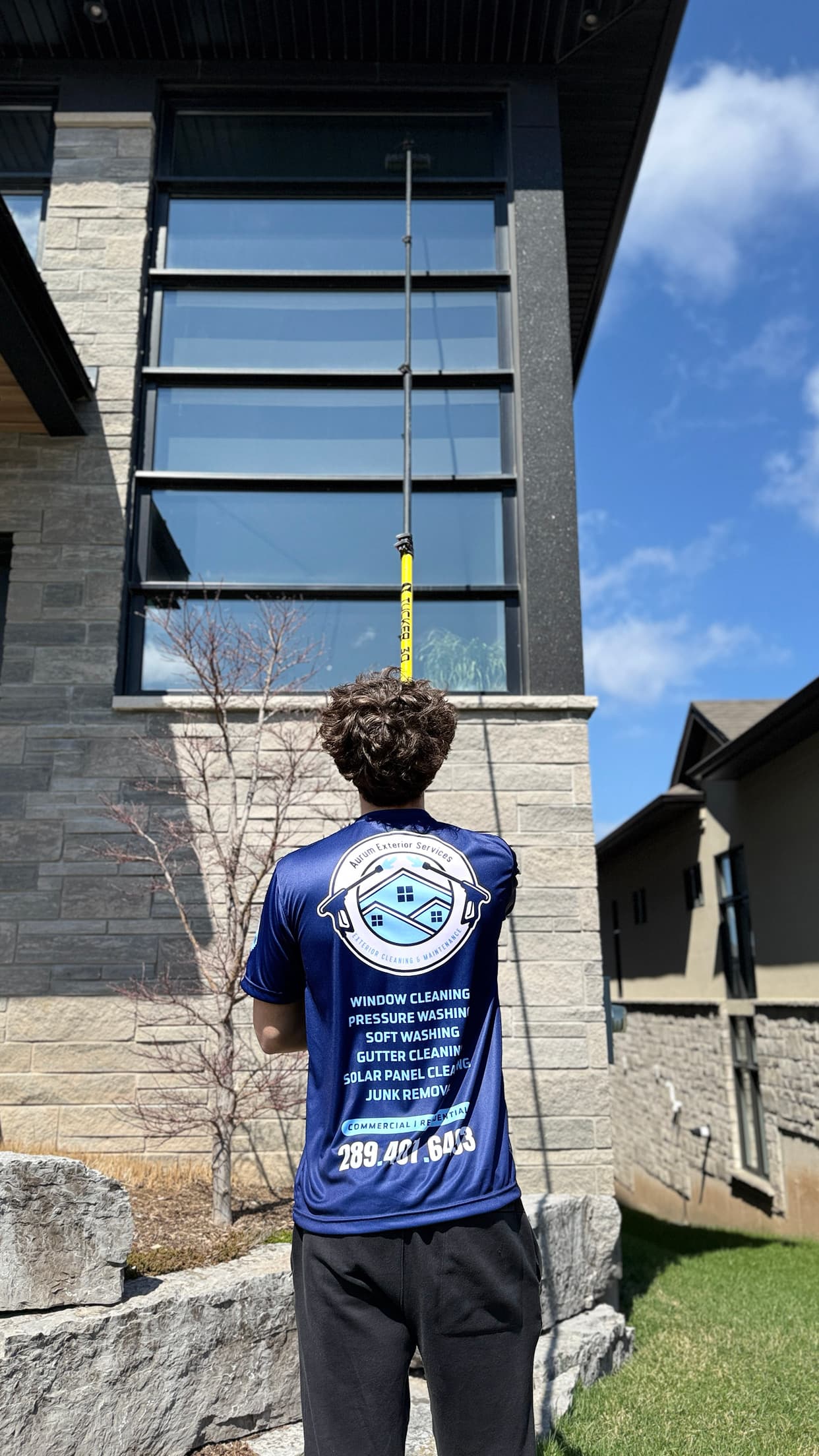 Aurum technician cleaning tall exterior windows with a water-fed pole